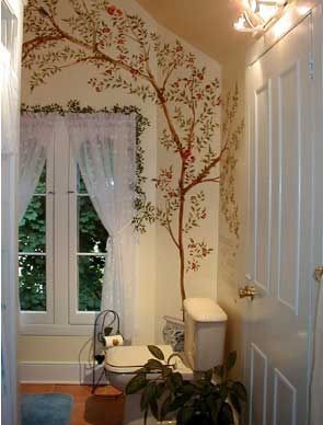 A bathroom with a toilet and a tree painted on the wall