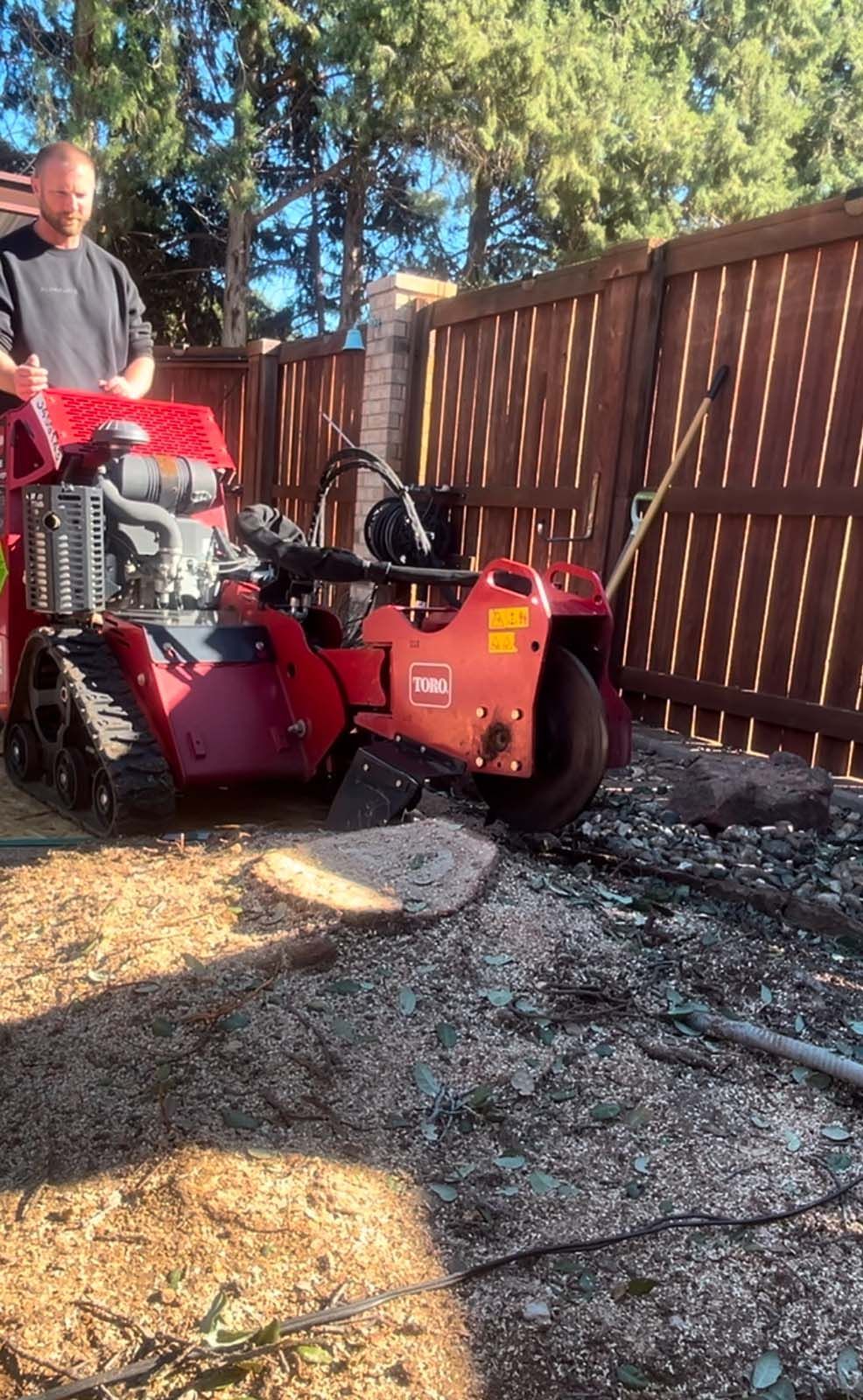 A man is using a tractor to remove a tree stump.