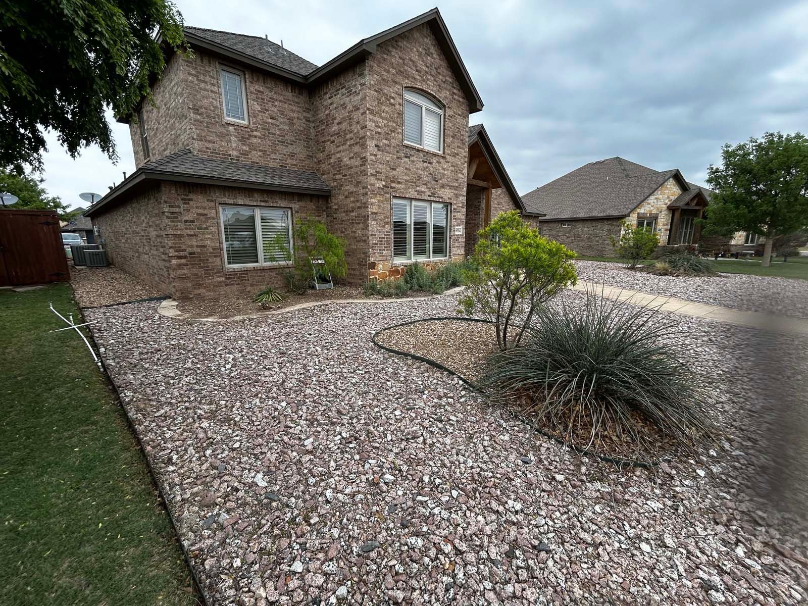 A large brick house with a gravel driveway in front of it.
