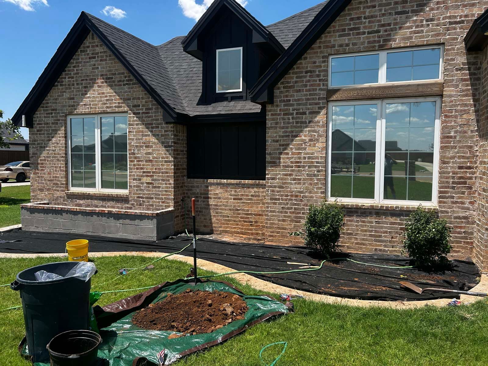 A brick house with a black roof and white windows is being built.