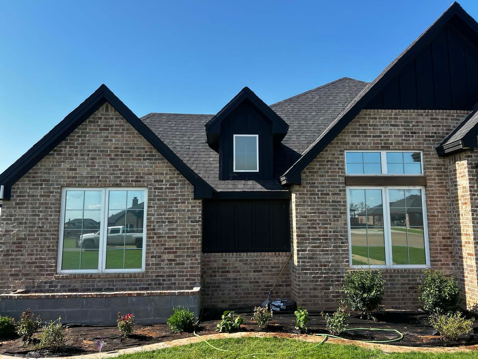 A brick house with a black roof and white windows