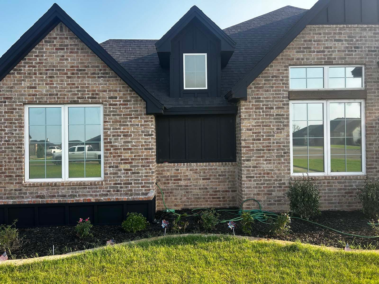 A brick house with a black roof and white windows