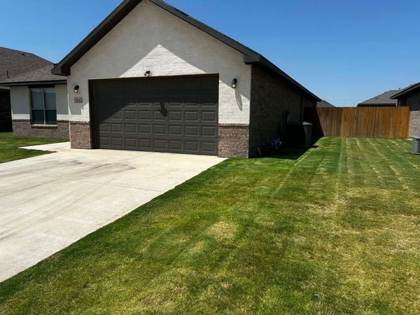 A house with a garage and a lush green lawn