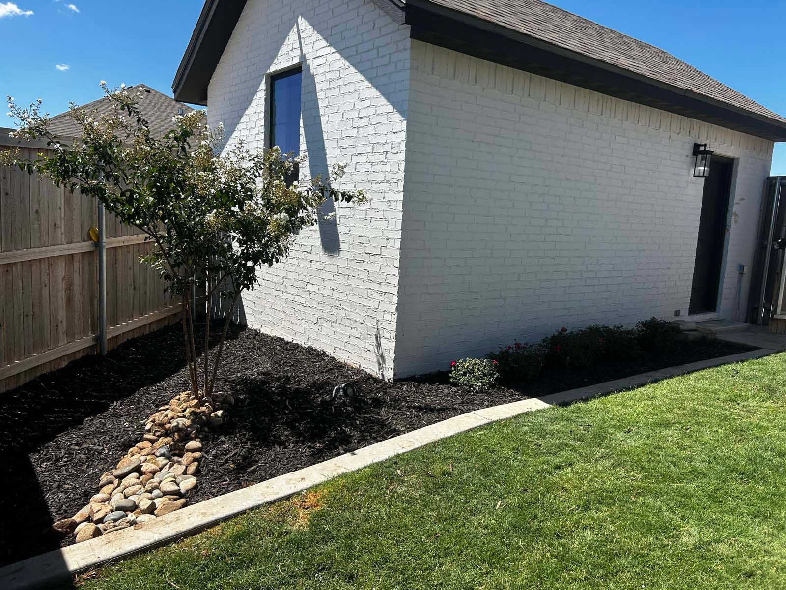 A white brick house with a wooden fence in the backyard.
