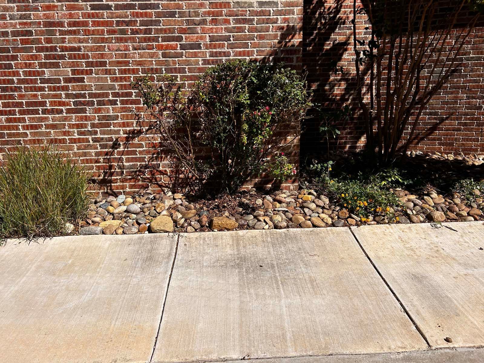A sidewalk with a brick wall in the background