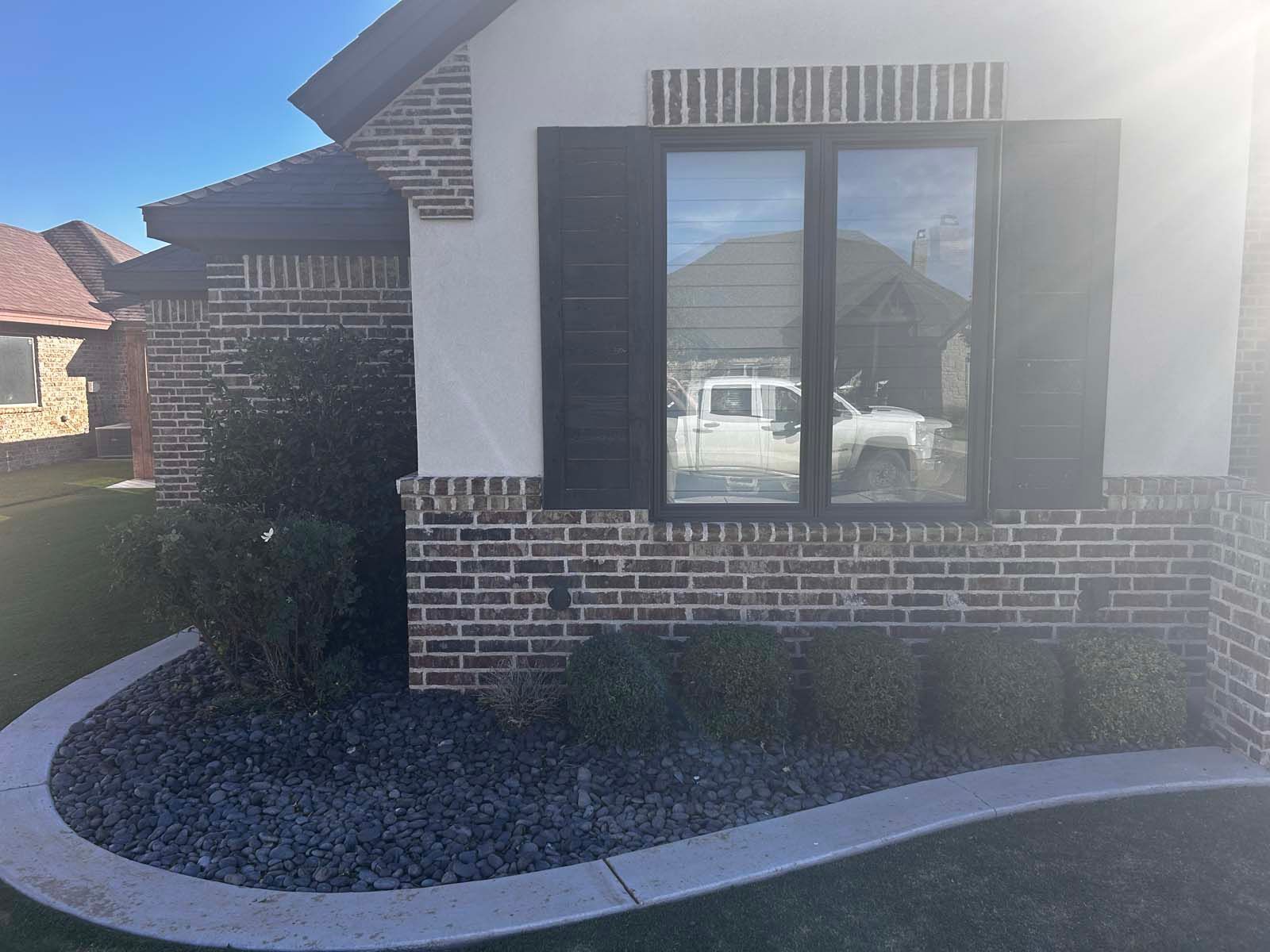 A white truck is parked in front of a brick house.