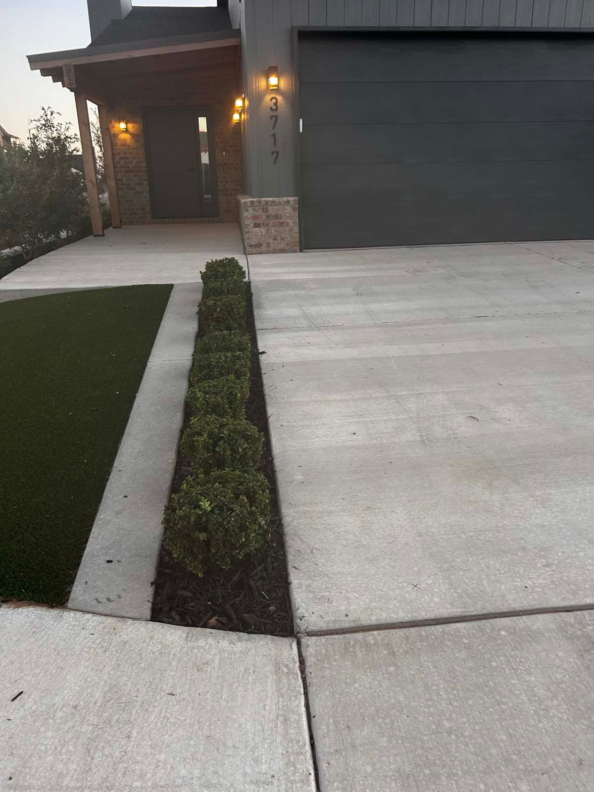 A concrete driveway leading to a house with a gray garage door.