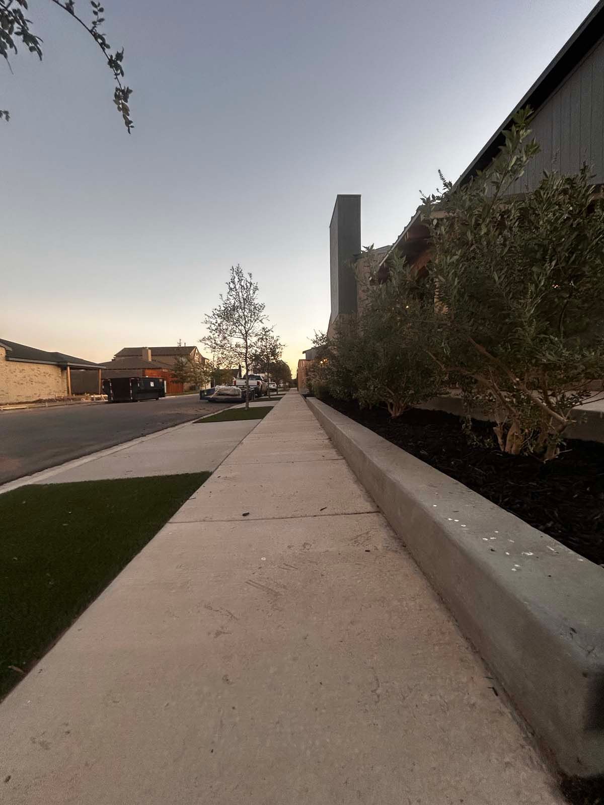 A sidewalk leading to a building with a tall building in the background