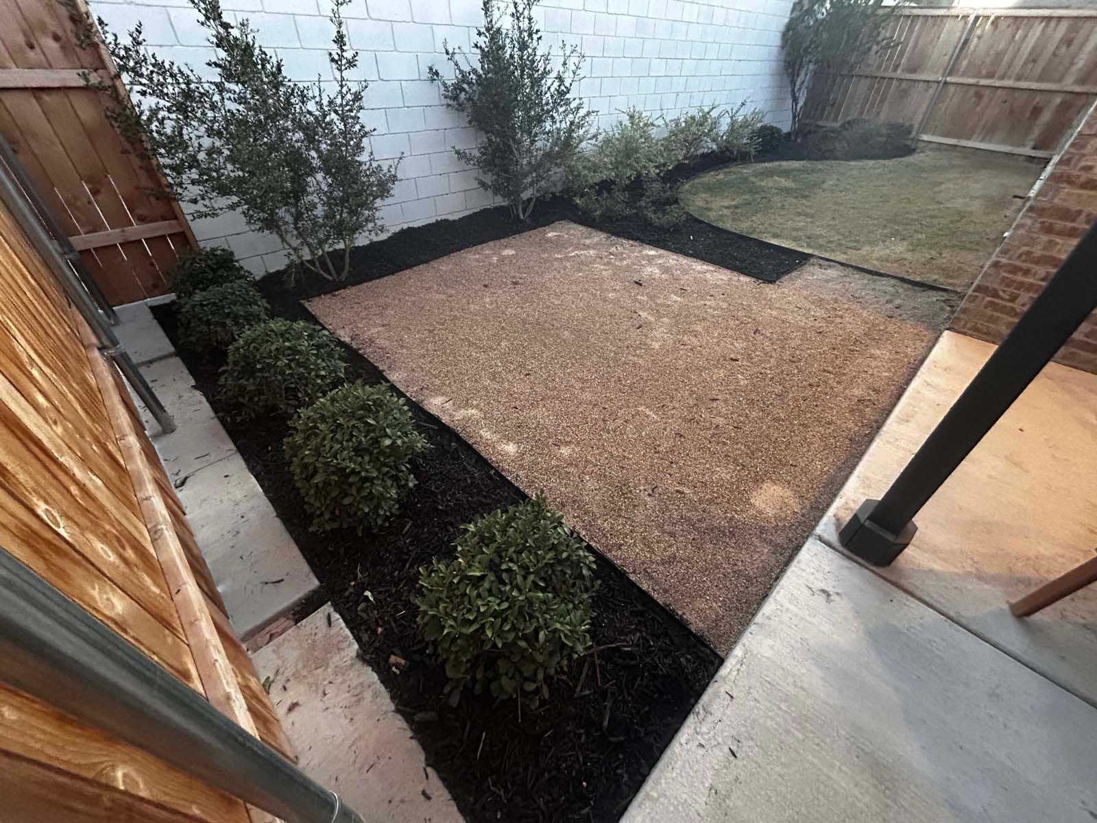 A small yard with a fence and bushes in it