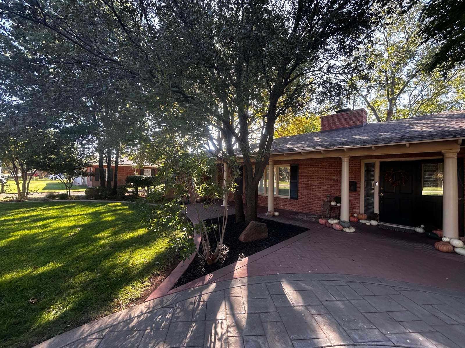 A brick house with a patio and trees in front of it