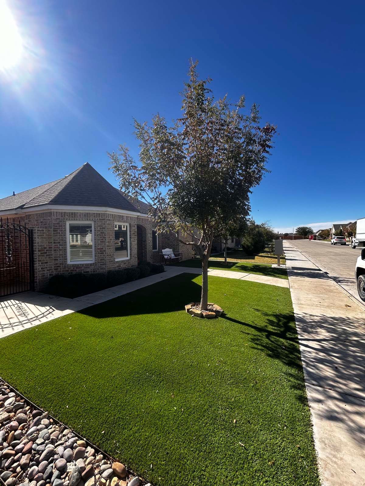 A house with a lush green lawn and a tree in front of it.