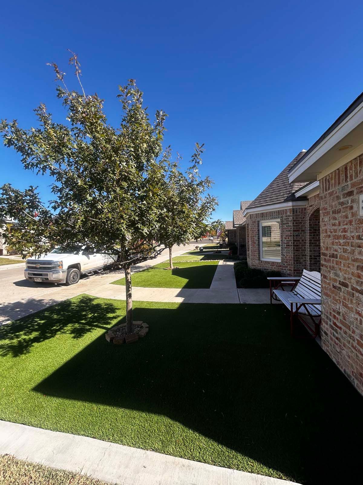A brick house with a bench and a tree in front of it.
