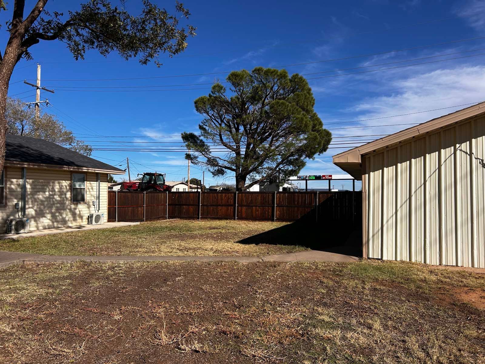 The backyard of a house with a fence and a tree