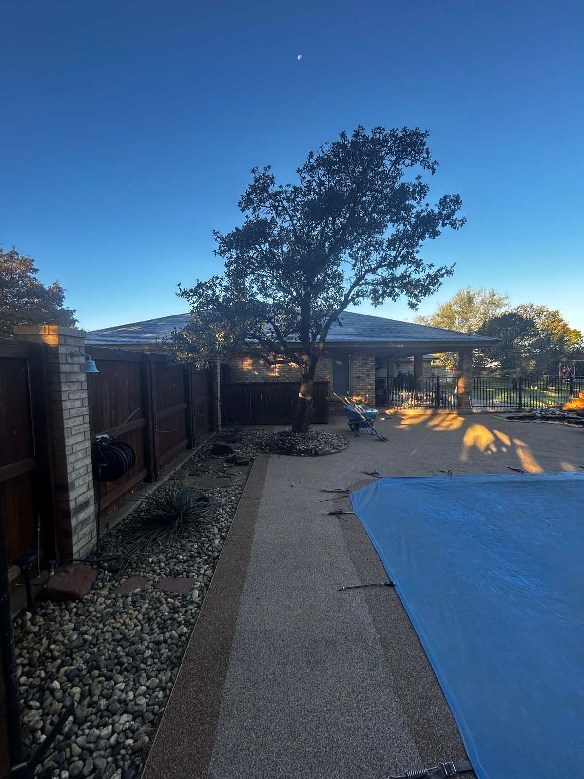 A blue tarp is covering a swimming pool in front of a house.