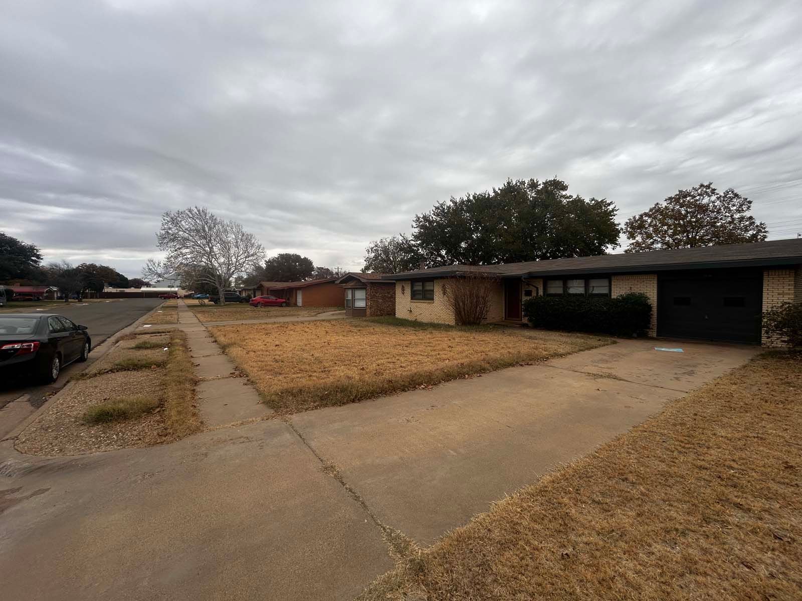 A car is parked in front of a house on a cloudy day
