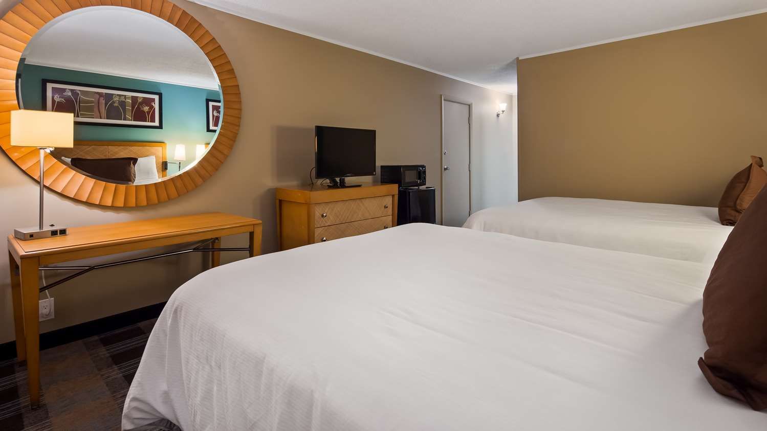 A hotel room with two beds and a large mirror