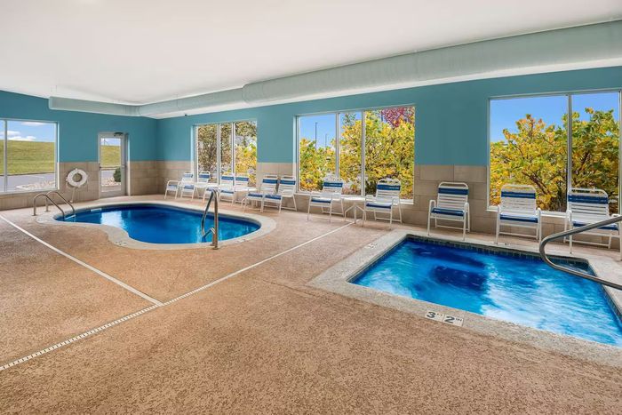 There is a swimming pool and a hot tub in the indoor pool area of a hotel.