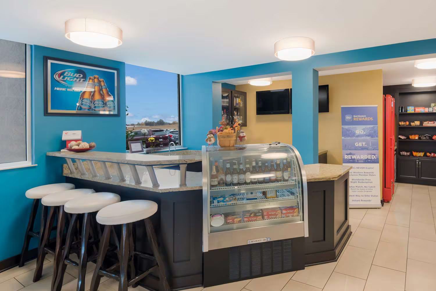 A hotel lobby with a bar , stools and a display case.