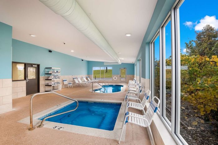 A large indoor swimming pool surrounded by chairs and windows.