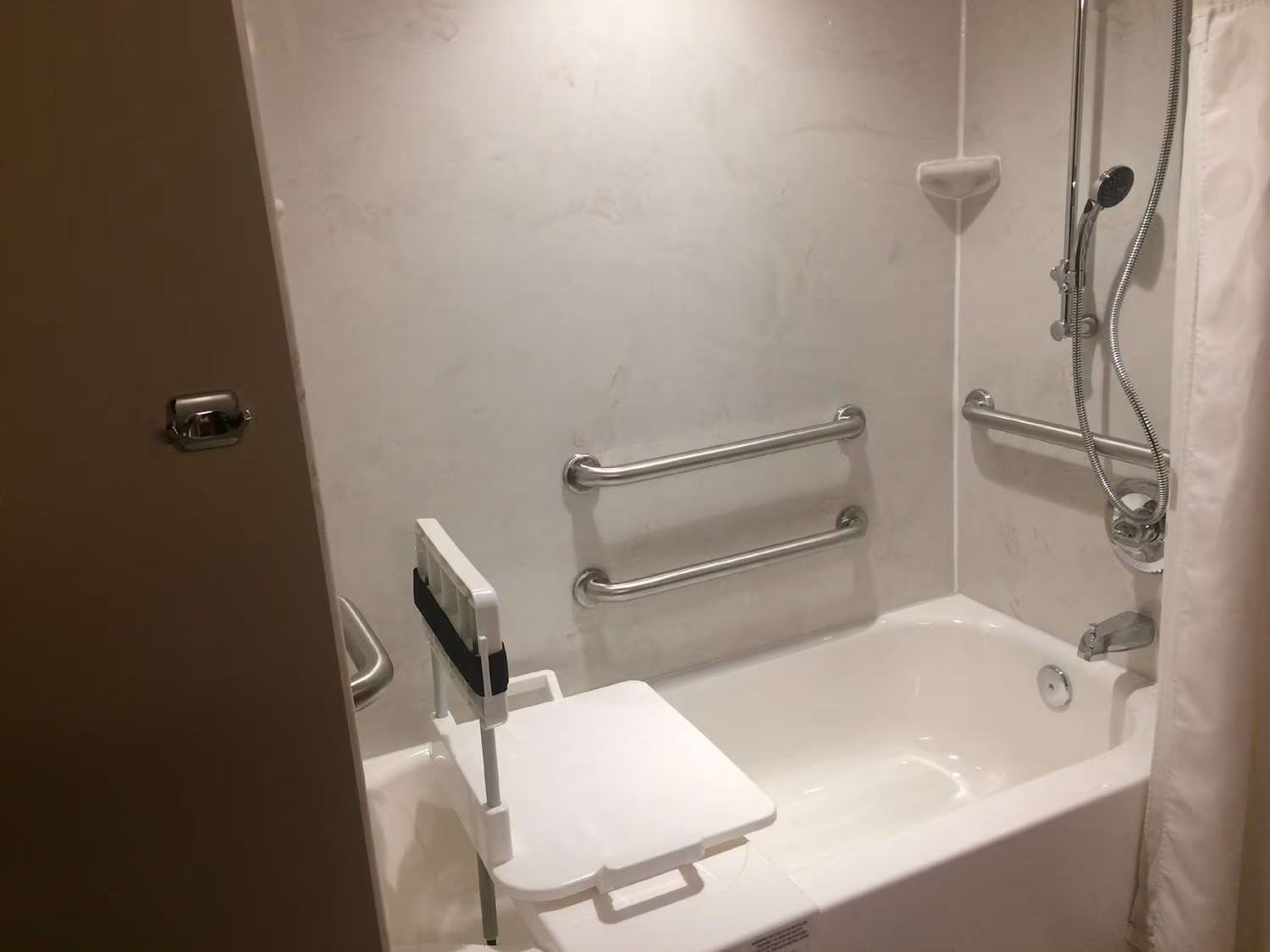 Bathtub with installed safety features like grab bars and a transfer bench.