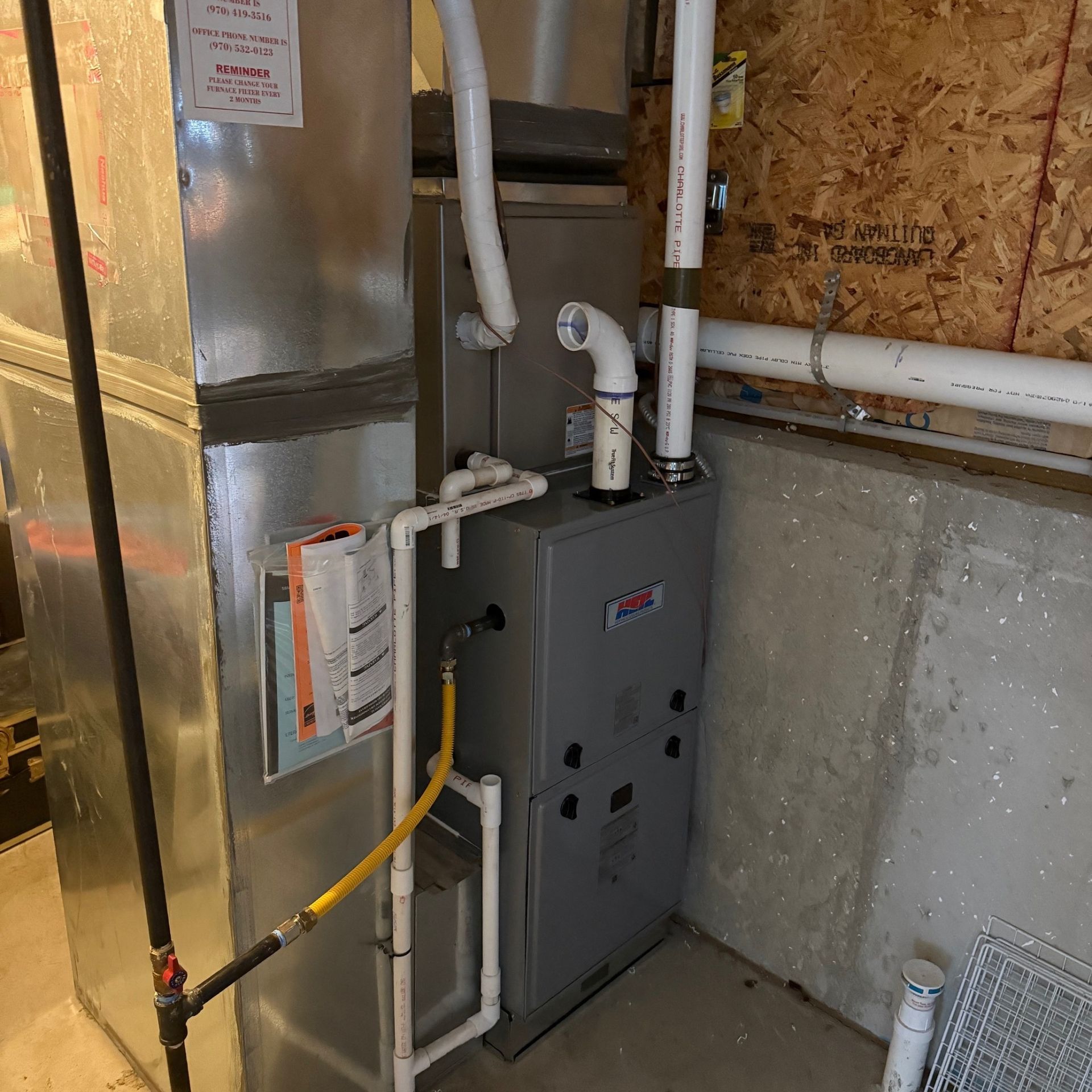 E.Squared Custom Plumbing Heating and Air - Furnace and ductwork in a basement. Gray furnace, silver duct, 