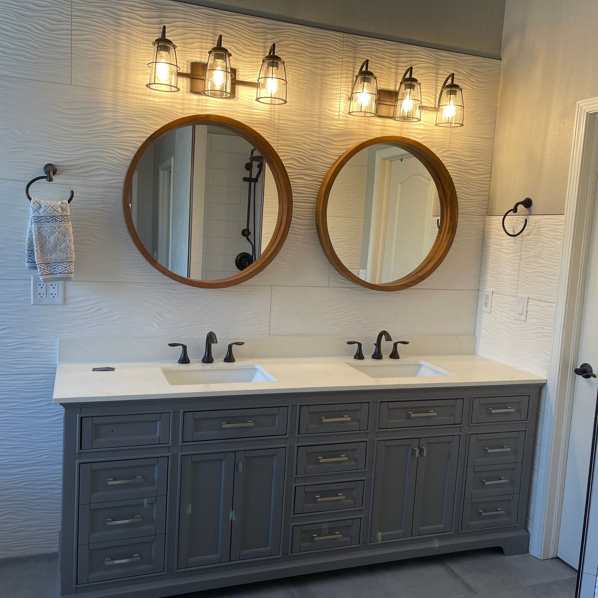 Plumber in orange gloves, blue shirt, tightening pipes under a white sink in a bathroom.