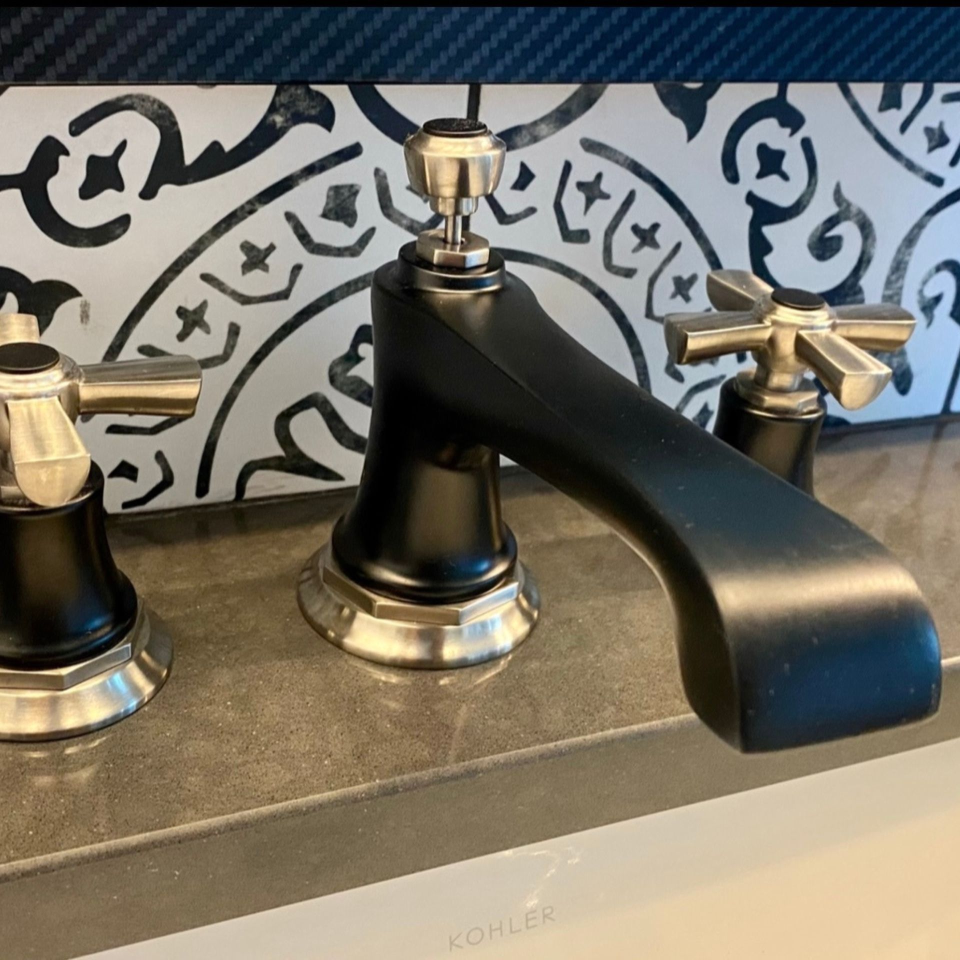 E.Squared Custom Plumbing Heating and Air - Black and silver bathroom faucet with cross handles on a tiled backsplash.