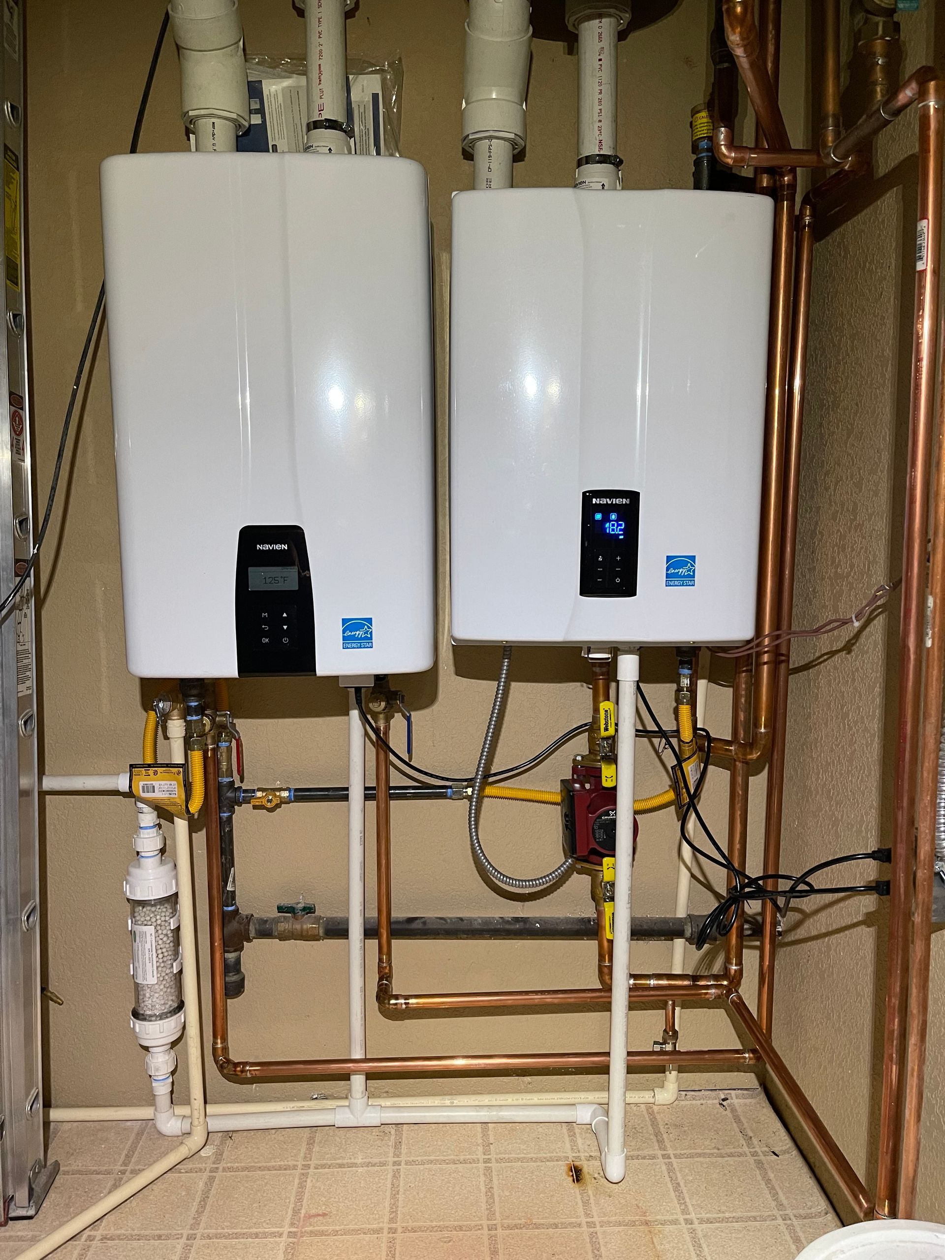 E.Squared Custom Plumbing Heating and Air - Two white tankless water heaters side-by-side, with copper pipes.