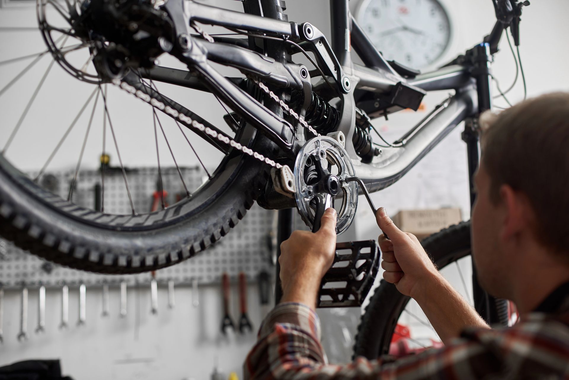 Persona che lavora con un attrezzo sugli ingranaggi di una bicicletta in un'officina.