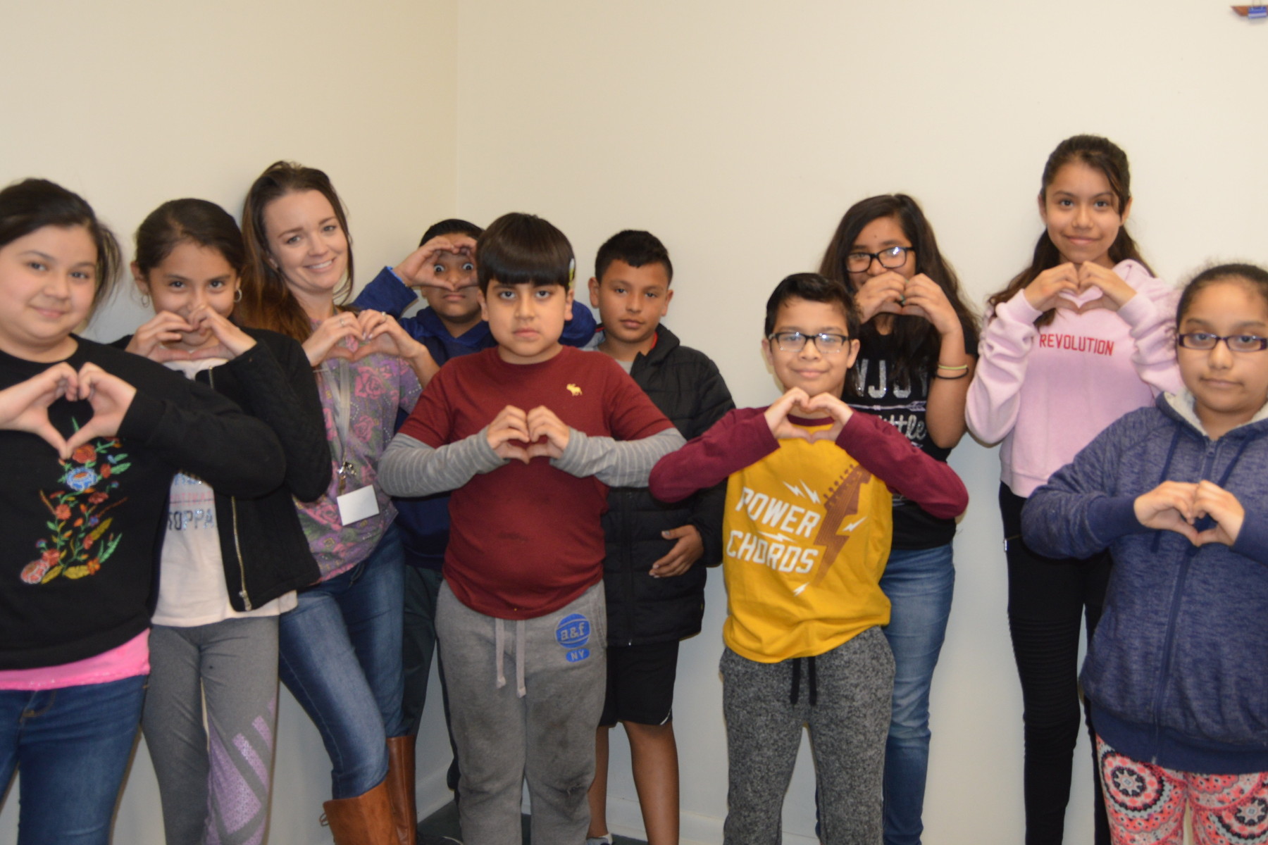 A group of children are making a heart shape with their hands