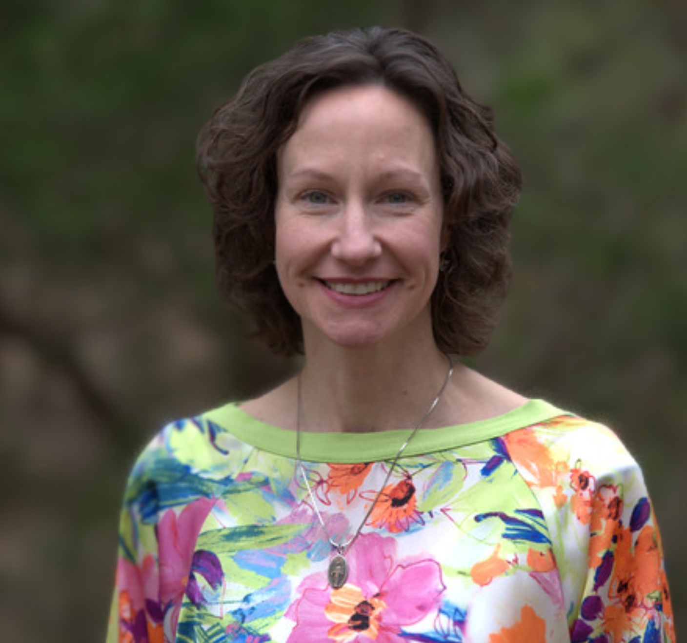 A lady wearing a floral shirt is smiling