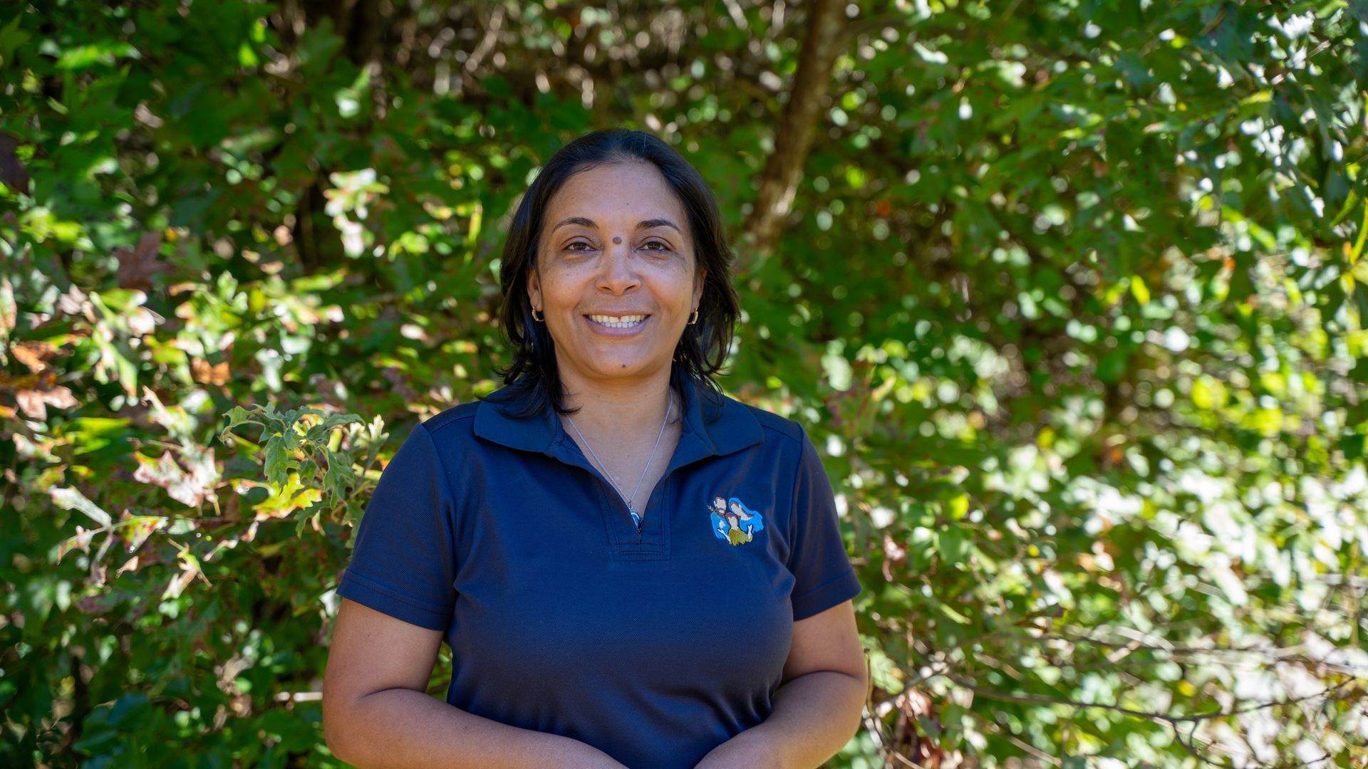 A woman with curly hair is smiling for the camera while wearing a colorful dress.