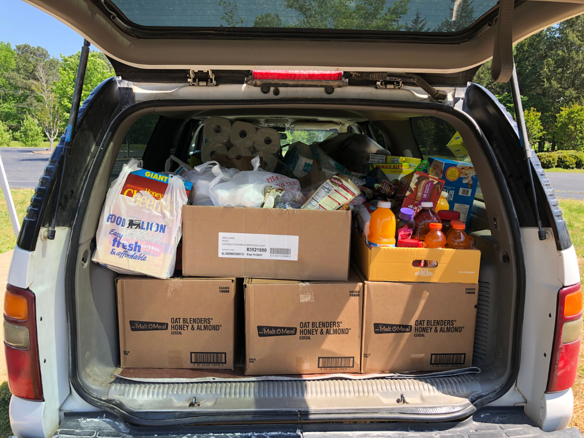 The trunk of a car is filled with boxes including one that says supply