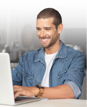 a man is smiling while using a laptop computer .