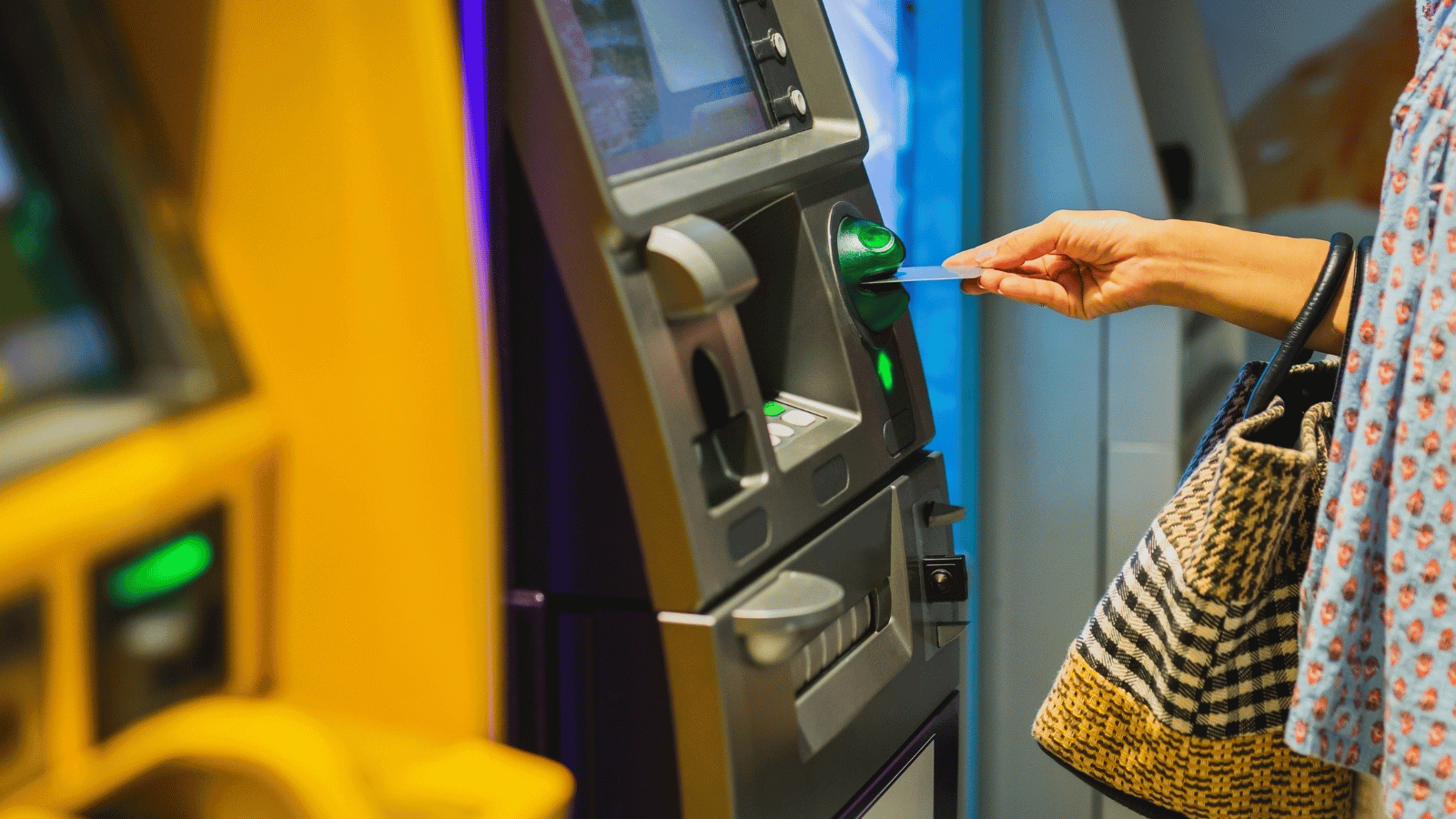 a woman is inserting a credit card into an atm machine .