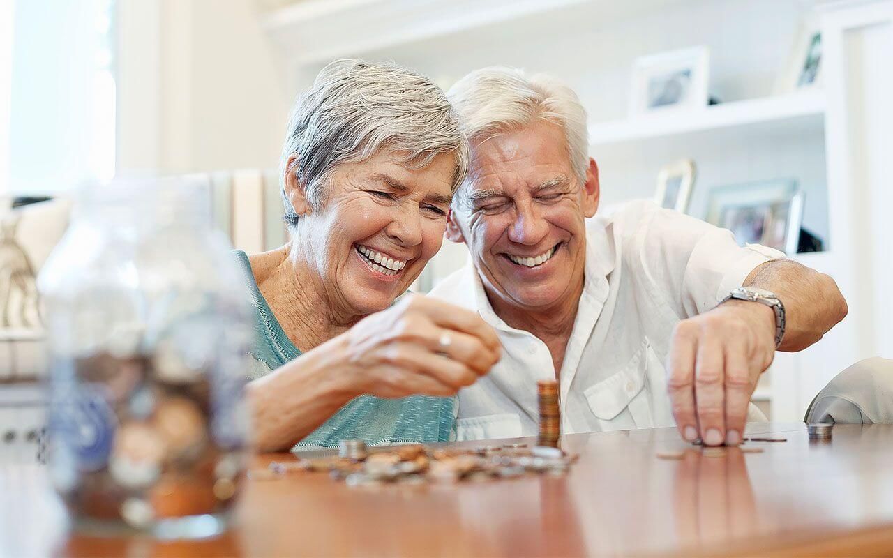 an elderly couple is sitting at a table counting coins .