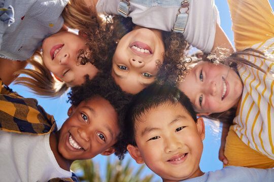 Group of smiling children leaning in a circle against a blue sky