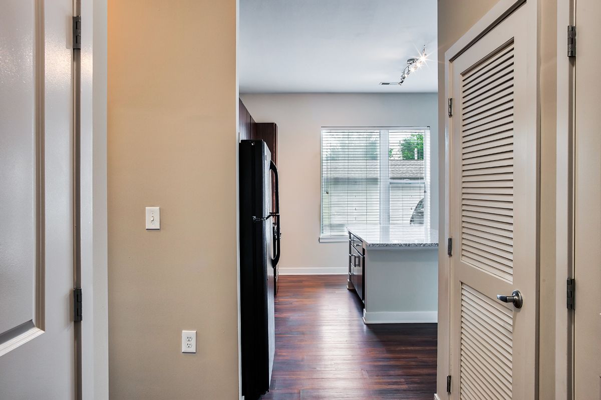 A hallway in a house leading to a kitchen and a refrigerator.