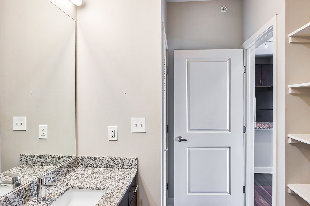 A bathroom with a sink , mirror and door