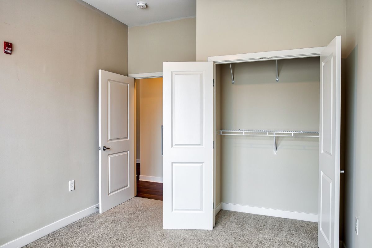 An empty bedroom with a walk in closet and a carpeted floor.