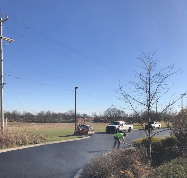 A man in a green vest is standing on the side of a road.