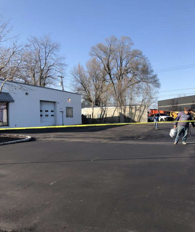 A man is walking down a street in front of a white building.