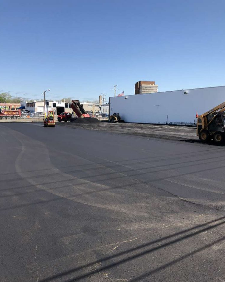 A large parking lot is being paved with a bulldozer.