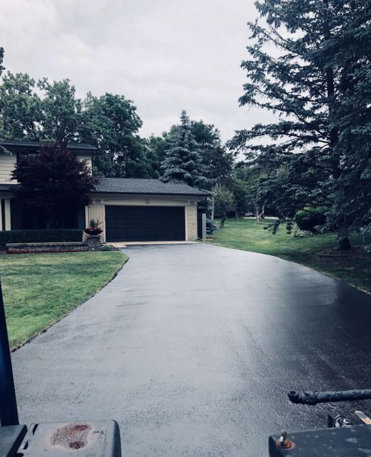 A driveway leading to a house with a black garage door