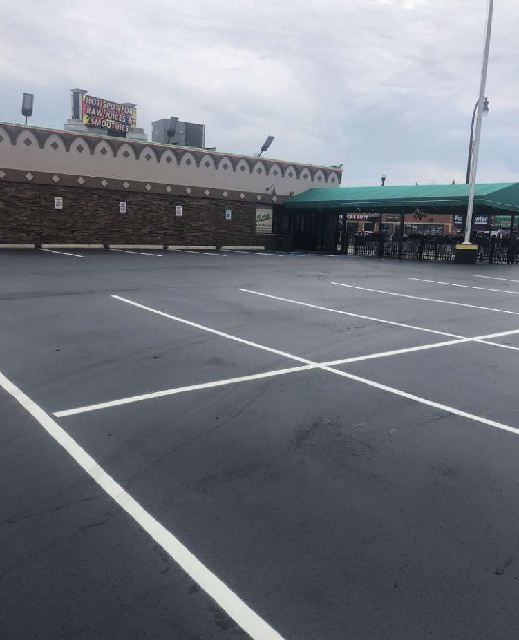 An empty parking lot in front of a building with a green roof