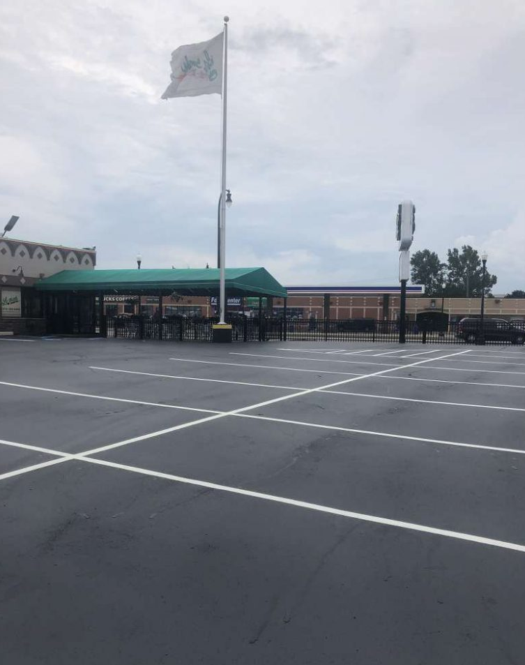 A parking lot in front of a building with a flag flying in the wind