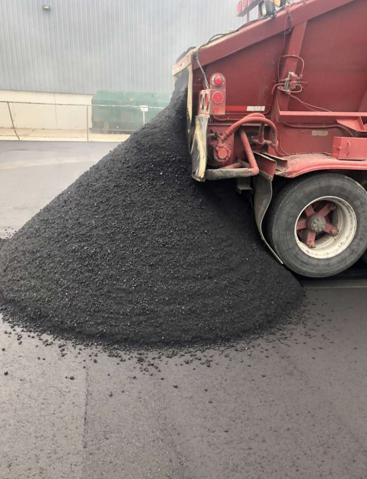 A dump truck is carrying a large pile of asphalt.