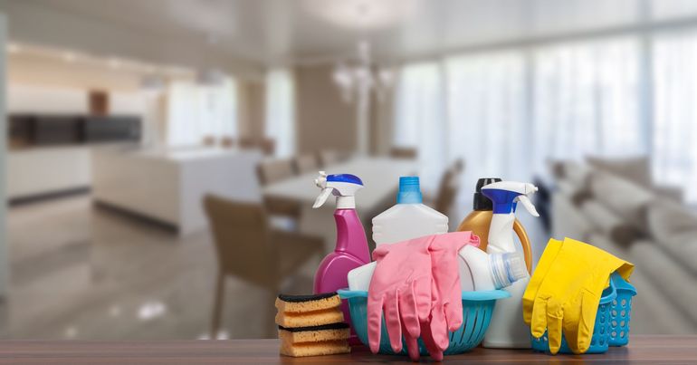 Cleaning supplies, gloves, and sponges on a table in a bright living room. Cleaning supplies, gloves, and sponges on a table in a bright living room.