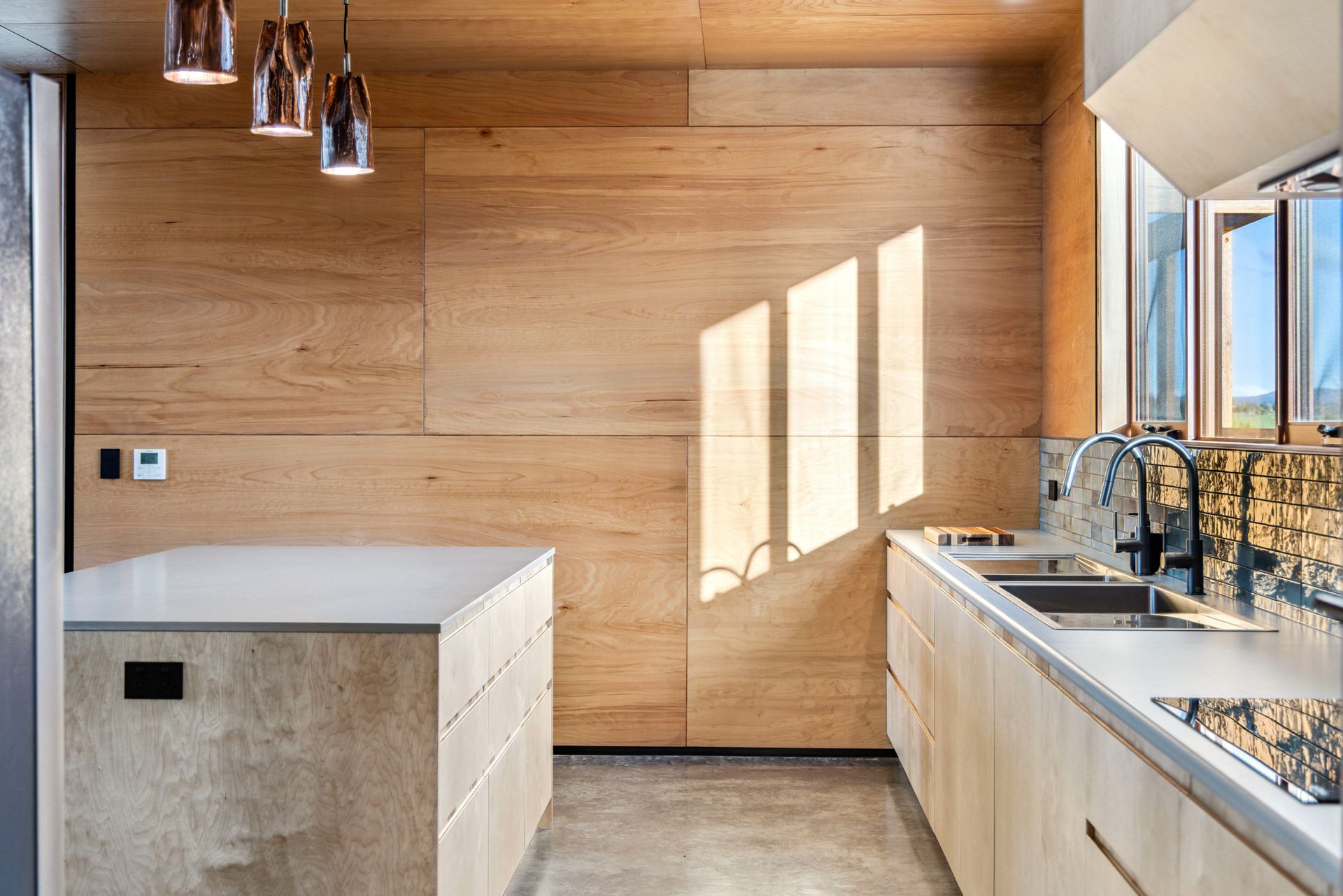 Modern kitchen with wood panel walls, island, countertops, and pendant lights— Croker Plumbing and Gas in Goulburn, NSW
