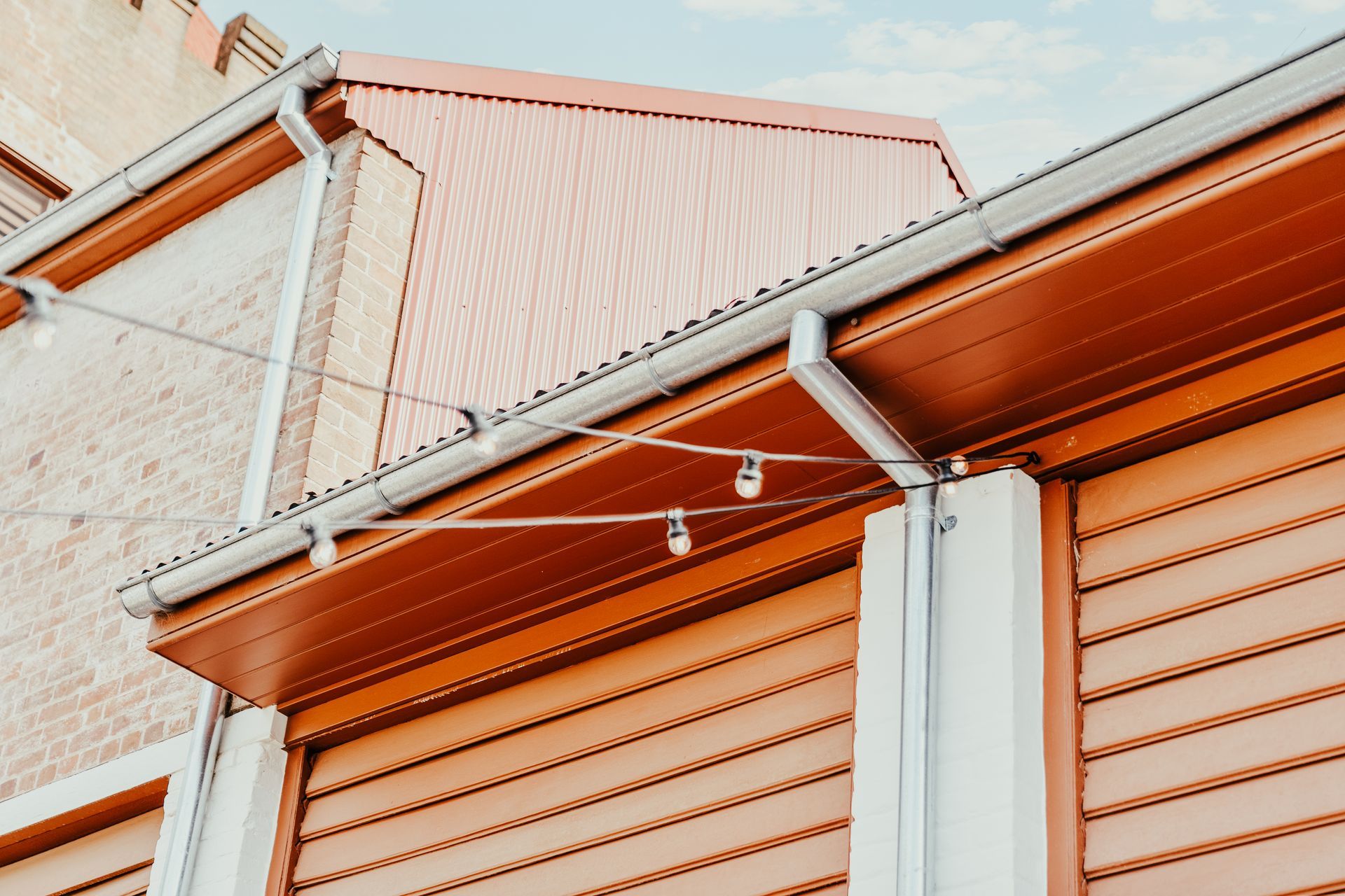 Orange building exterior with string lights and a blue sky.